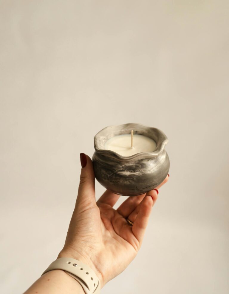 Aesthetic photo of a hand holding a ceramic candle with soft, natural lighting, perfect for decor inspiration.