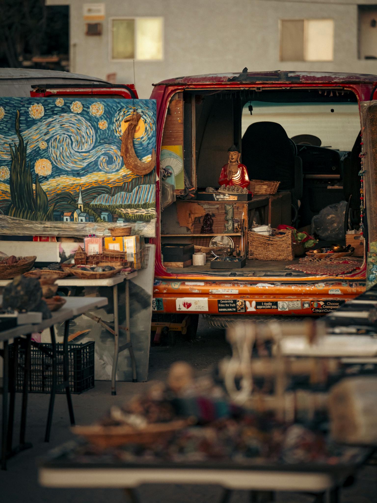 Bohemian market scene with art, candles, and decor displayed from the back of a van.